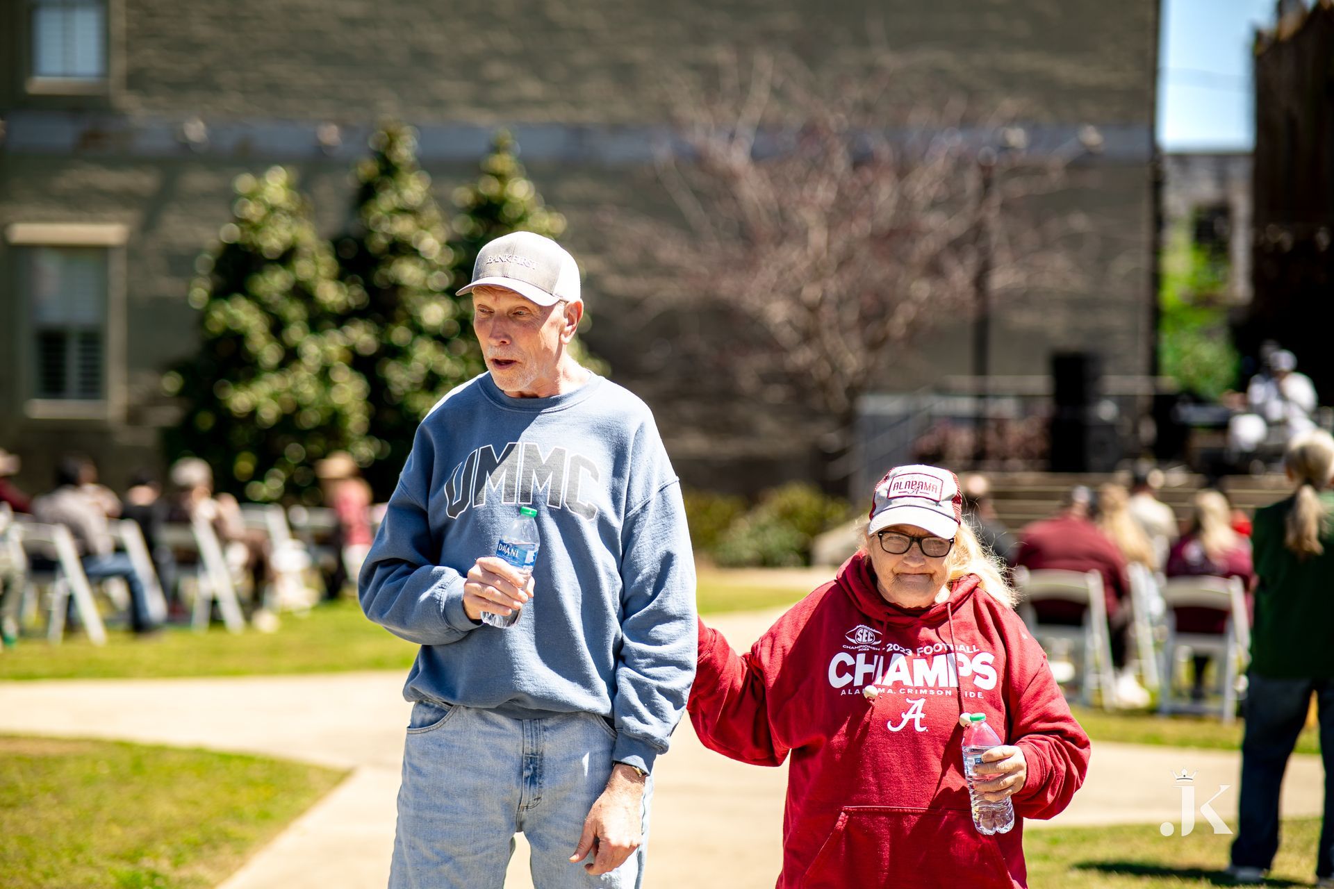 A man and a woman are walking down a sidewalk holding hands.