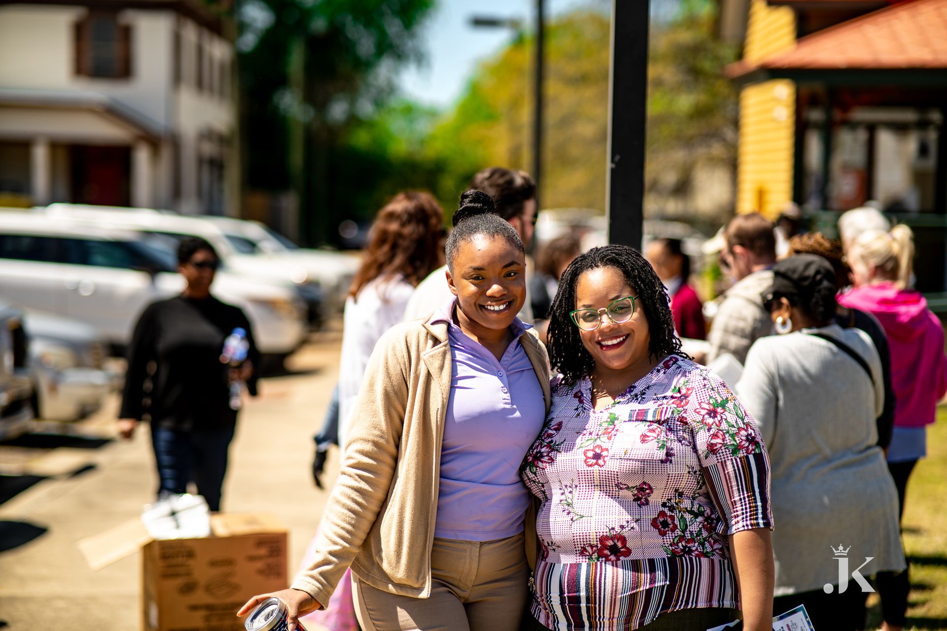 Two women are posing for a picture in front of a crowd of people.