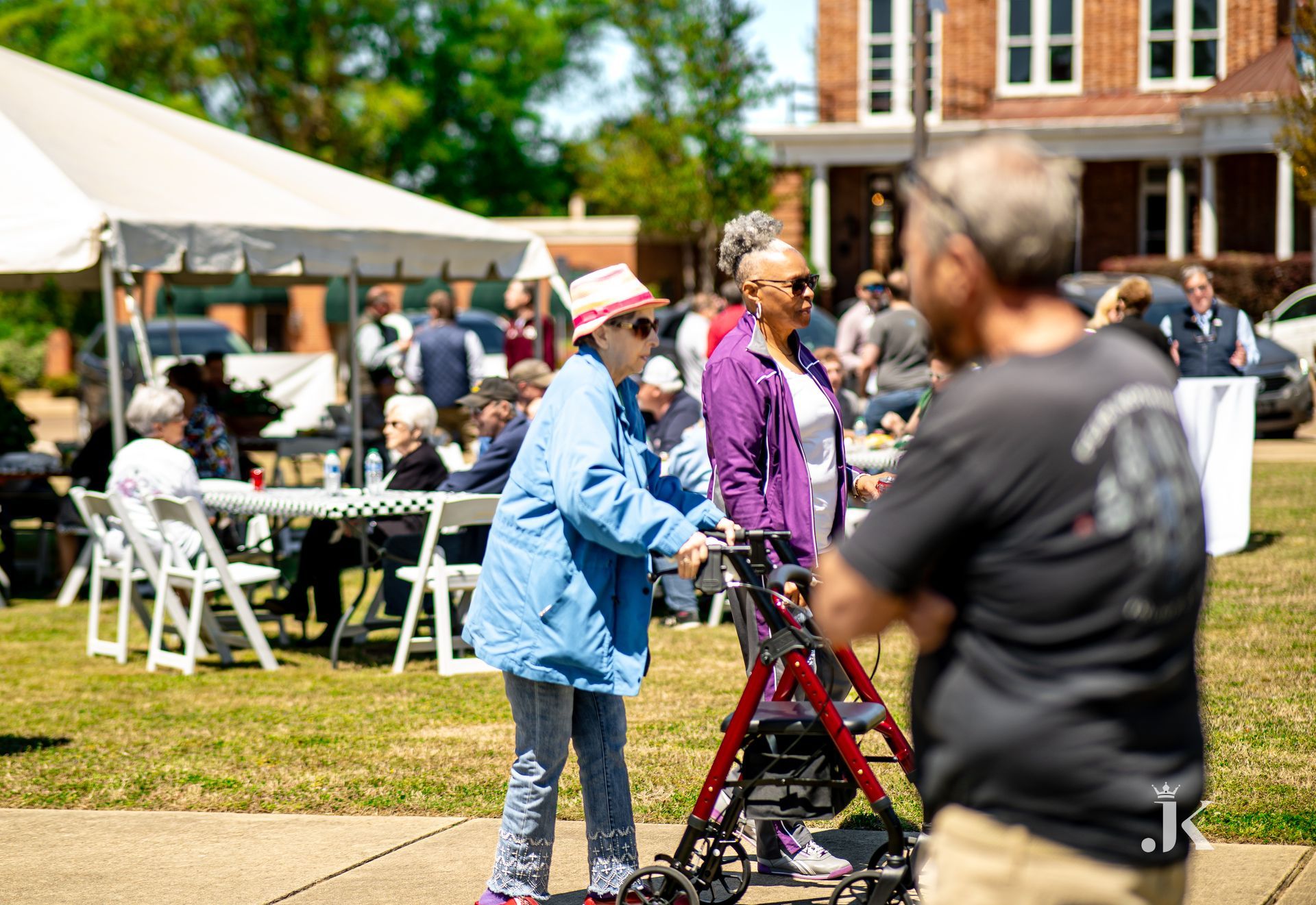 An elderly woman is walking with a walker in a park.