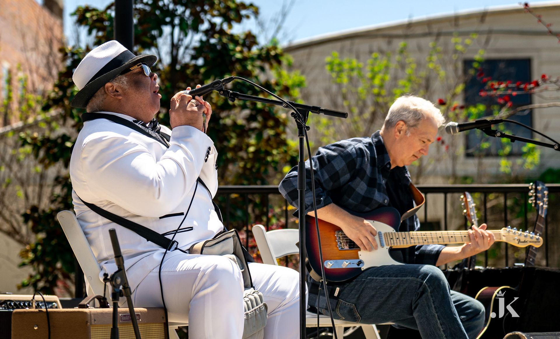 Two men are playing guitars and singing into microphones on a stage.