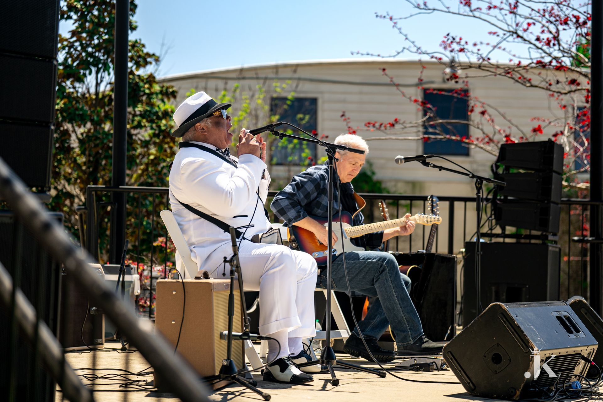 Two men are playing guitars and singing on a stage.