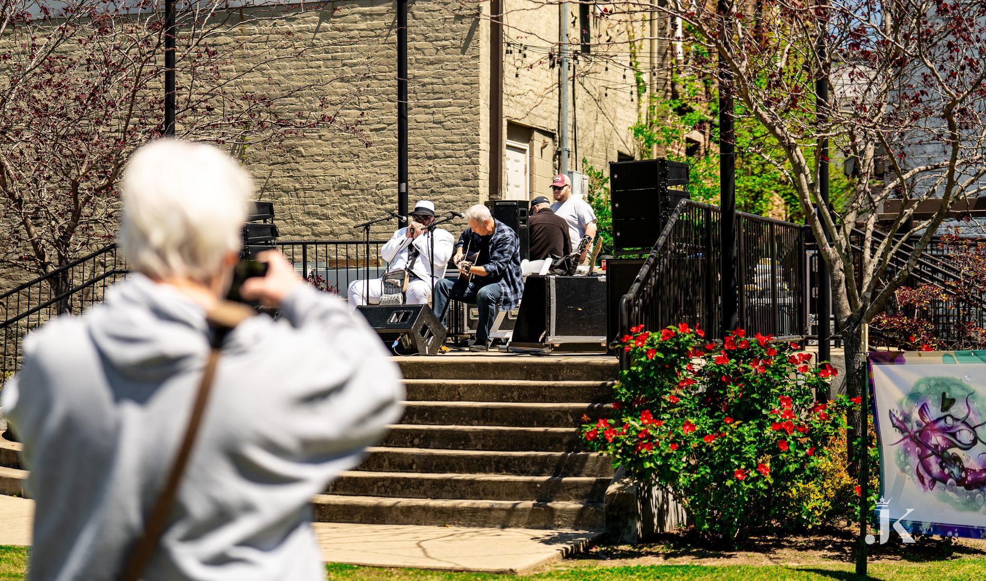 A man is taking a picture of a group of people playing instruments in a park.