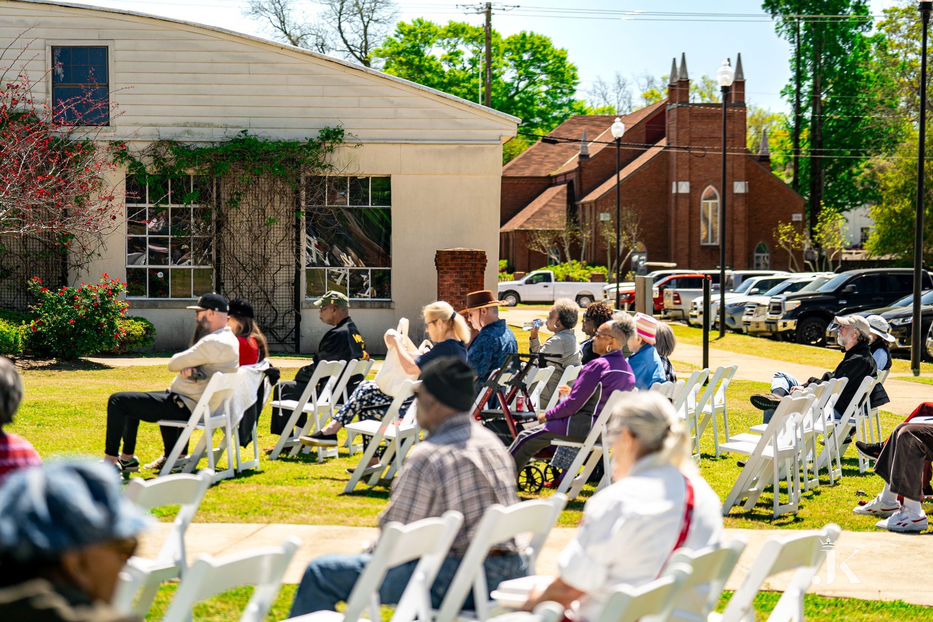A group of people are sitting in white chairs in front of a building.