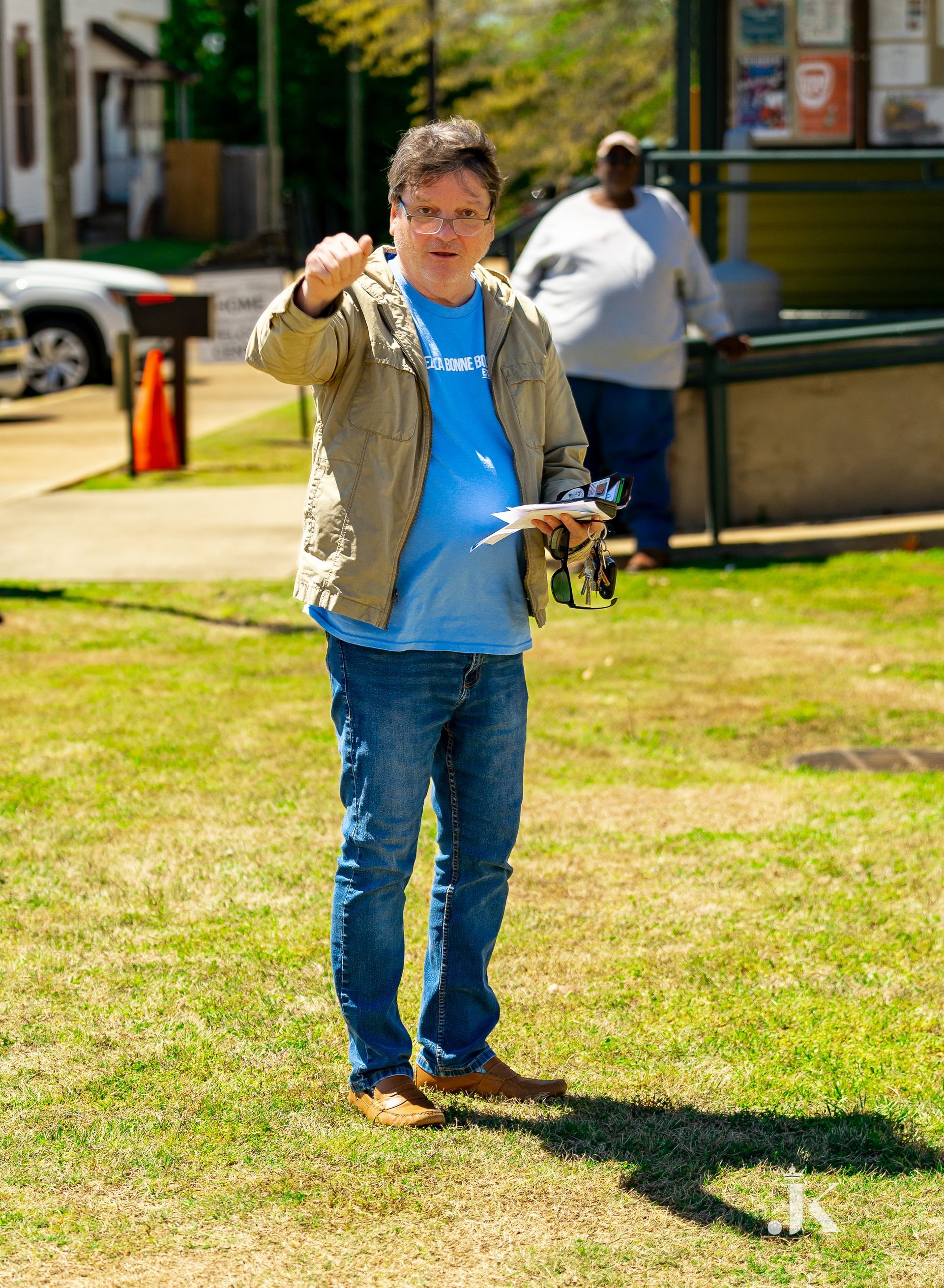 A man is standing in the grass holding a remote control.