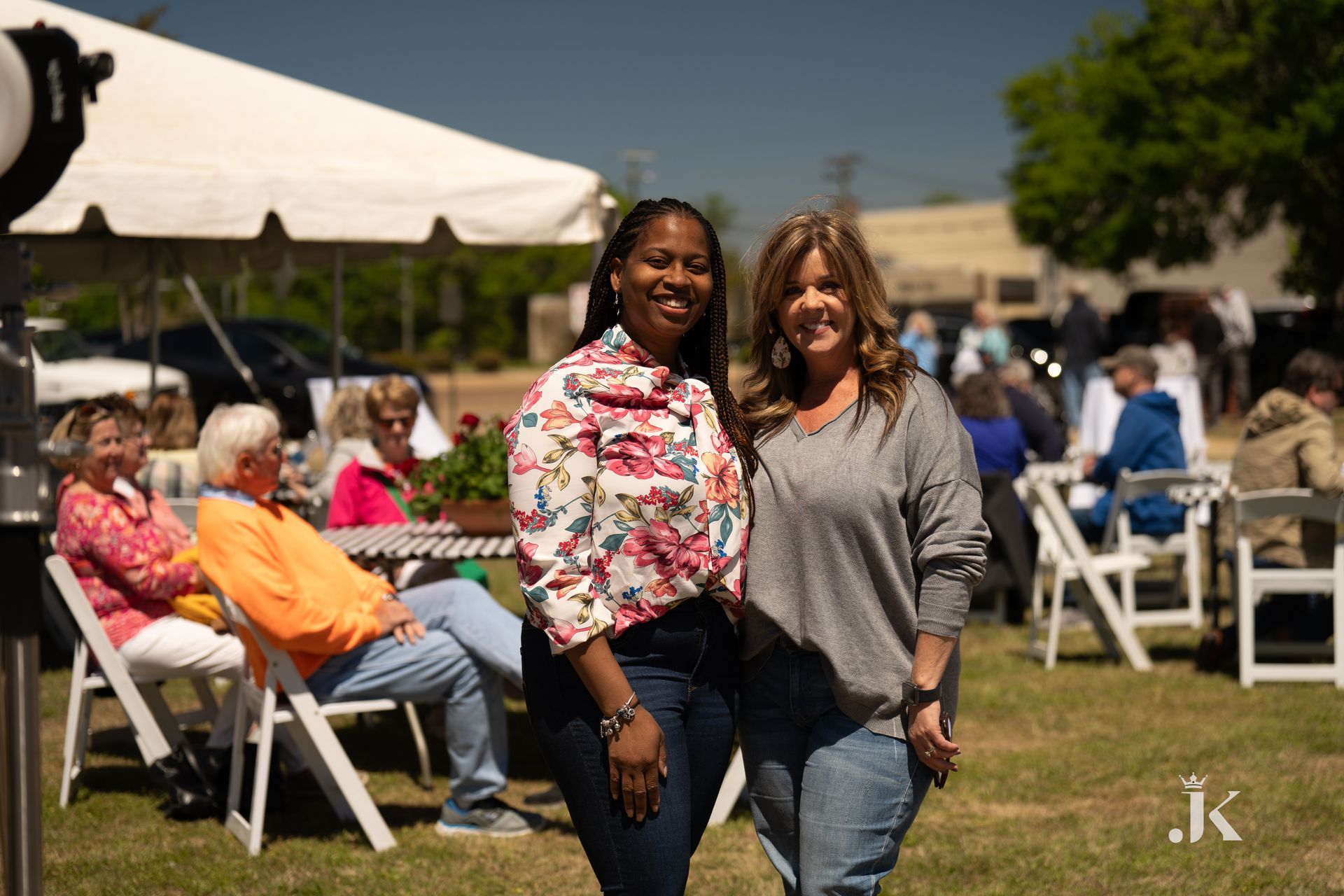 Two women are standing next to each other in a field holding hands.
