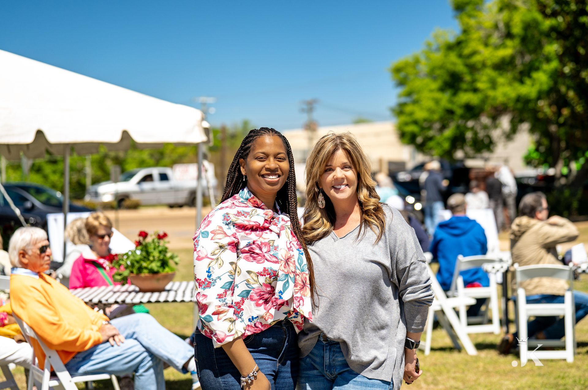 Two women are posing for a picture in front of a crowd at a picnic.