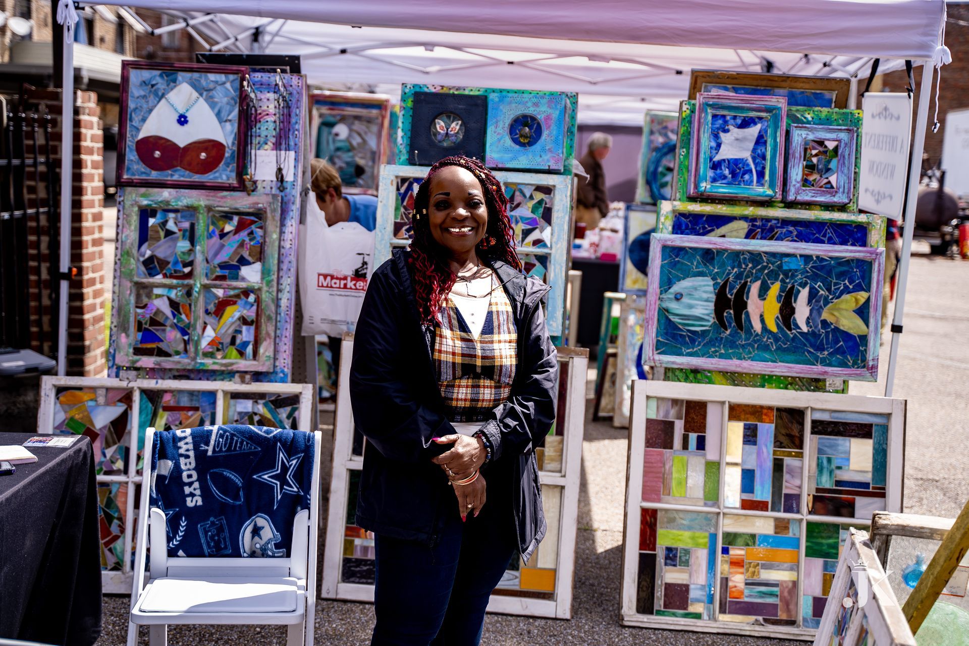A woman is standing in front of a tent filled with paintings.