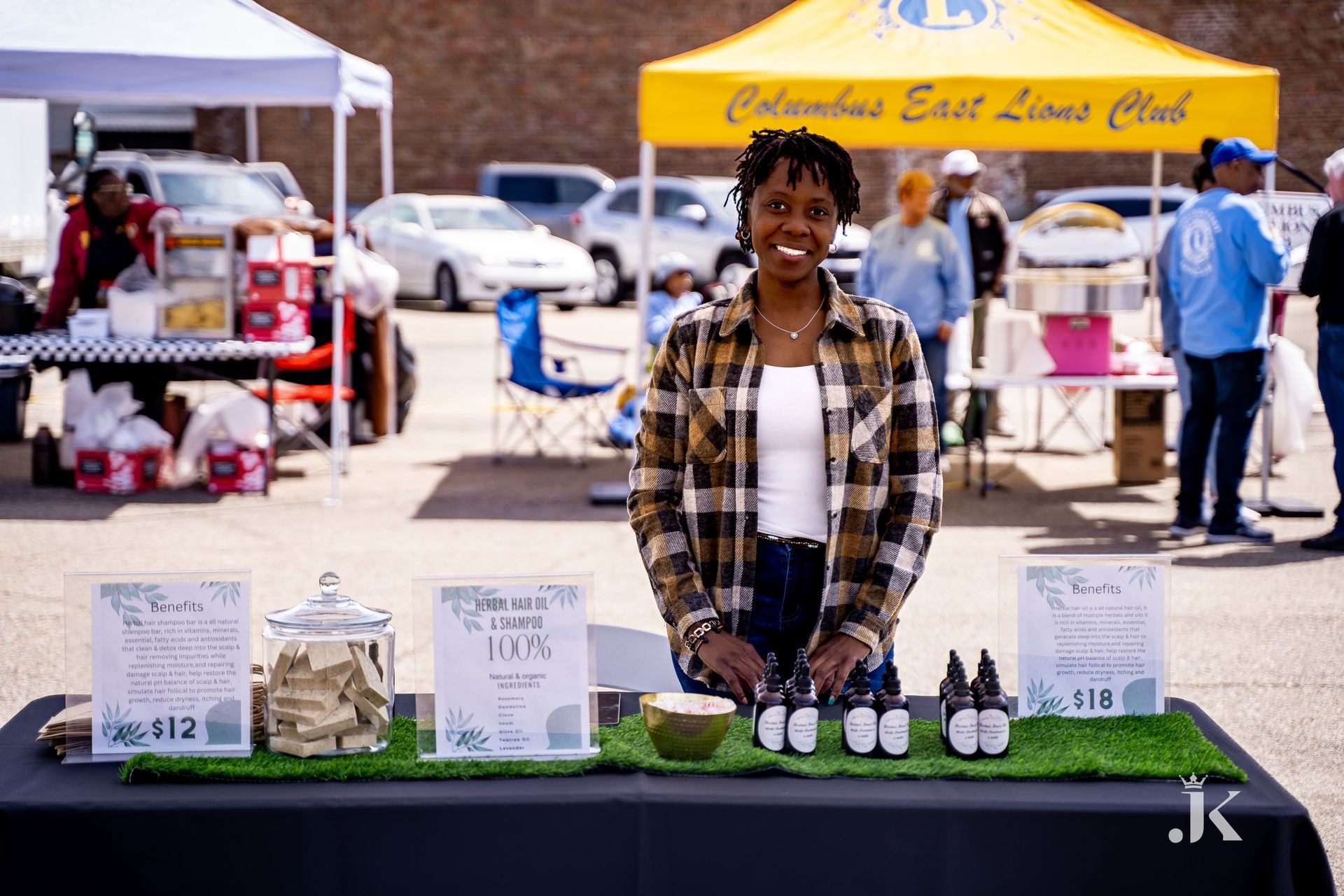 A woman is standing behind a table at a market.