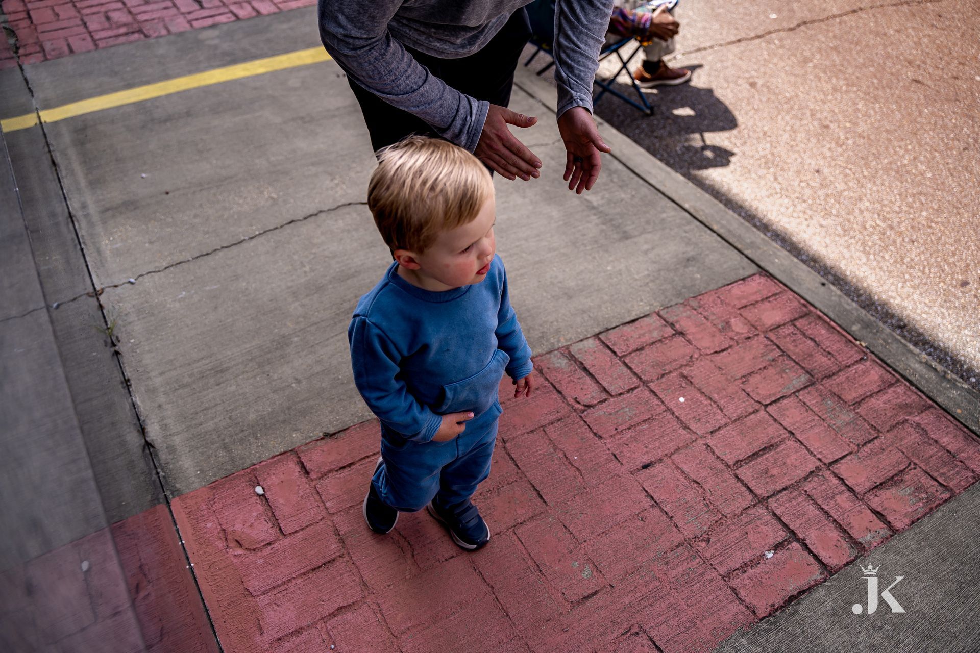 A man and a little boy are walking down a sidewalk.