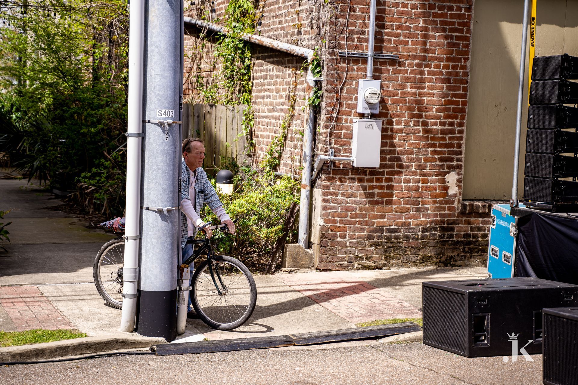 A man is riding a bike on a sidewalk next to a pole.