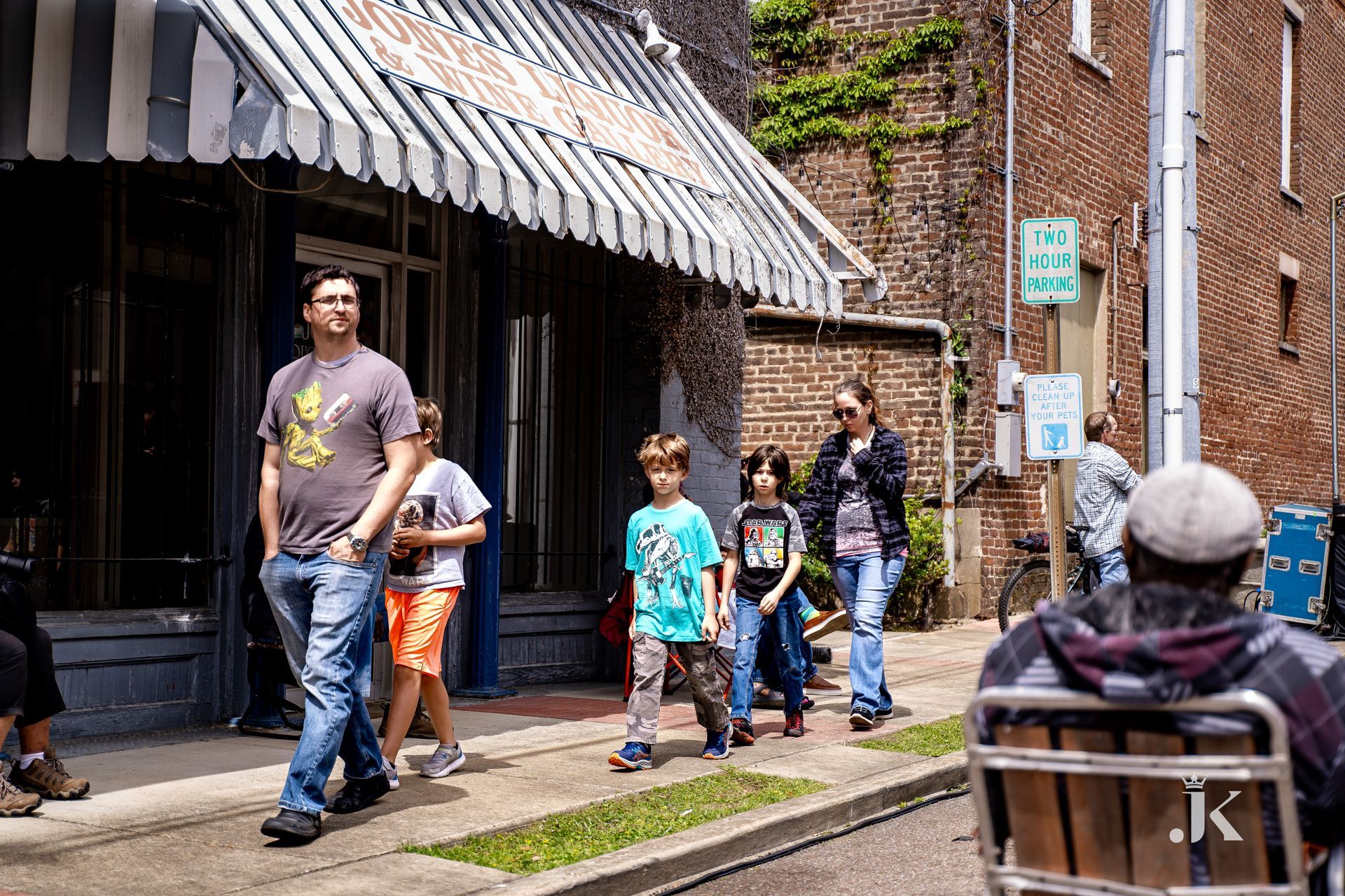 A group of people are walking down a sidewalk in front of a store.