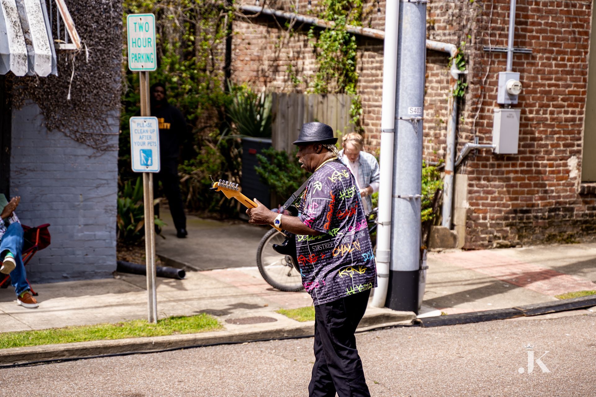 A man is playing a guitar on the side of the road.