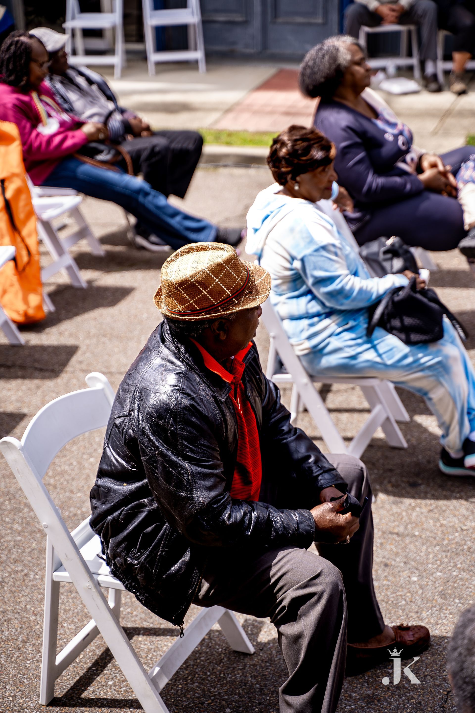 A group of people are sitting in white folding chairs.