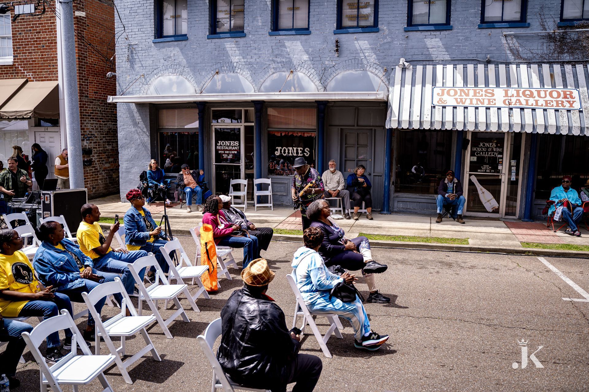 A group of people are sitting in chairs in front of a building.