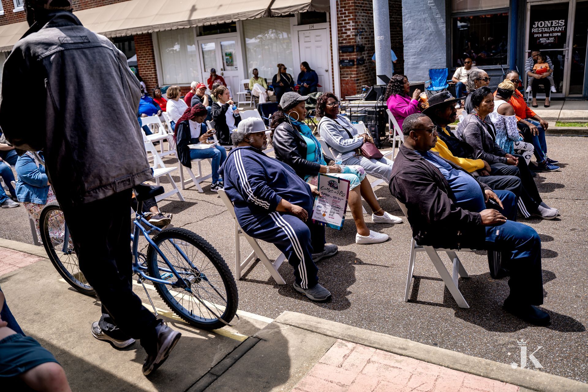 A group of people are sitting in chairs on the side of the road.