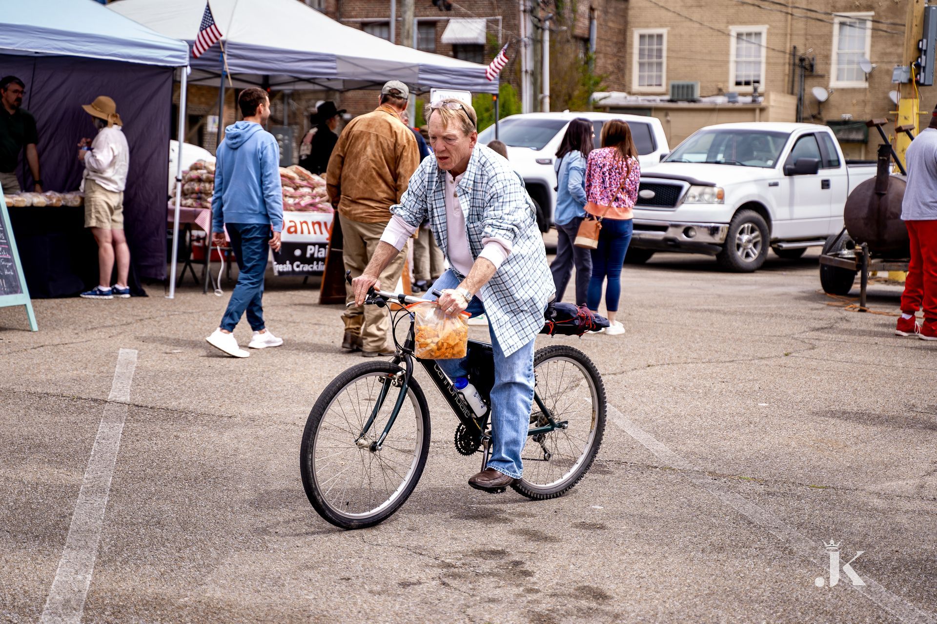 A man is riding a bike in a parking lot.