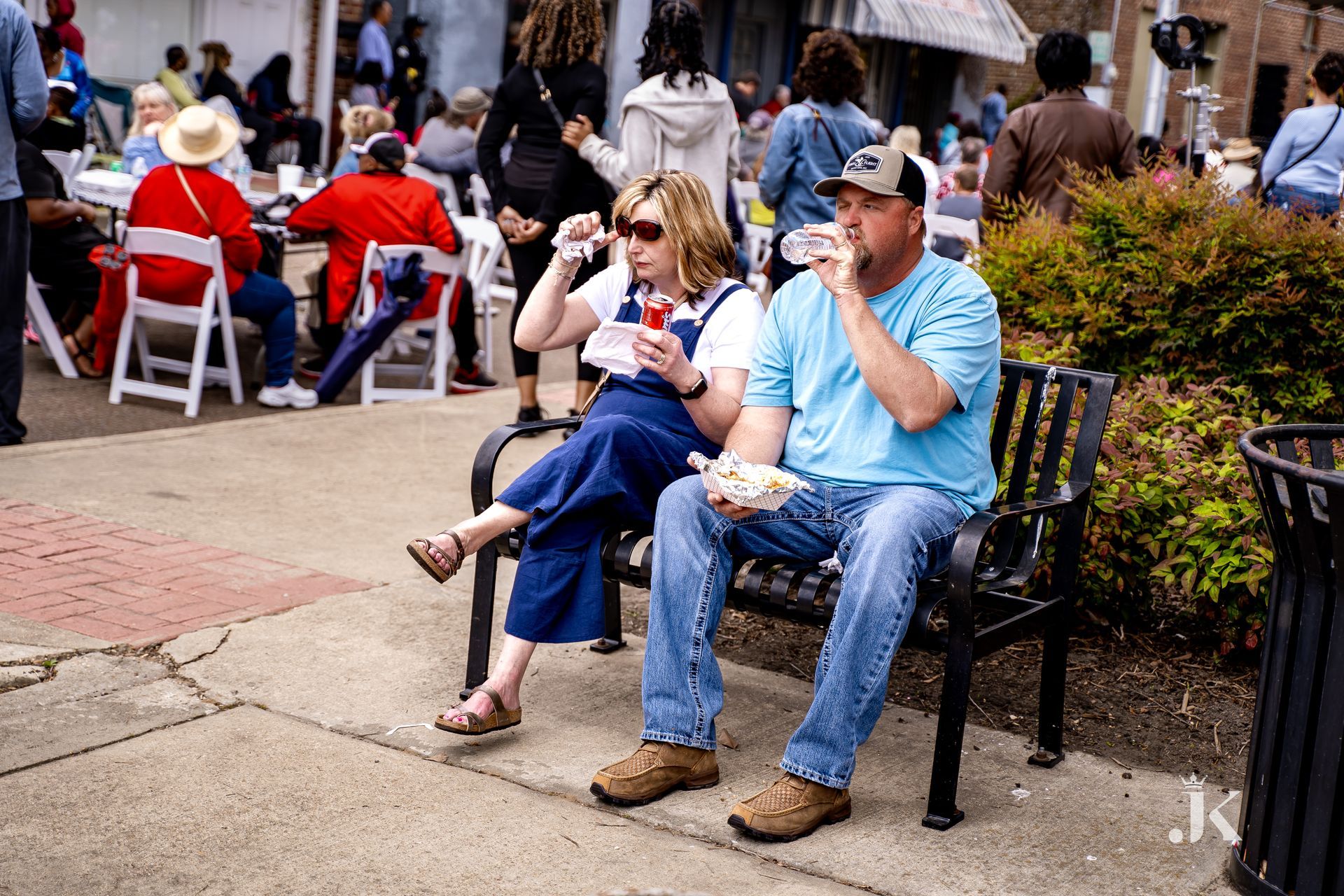 A man and a woman are sitting on a bench eating food.