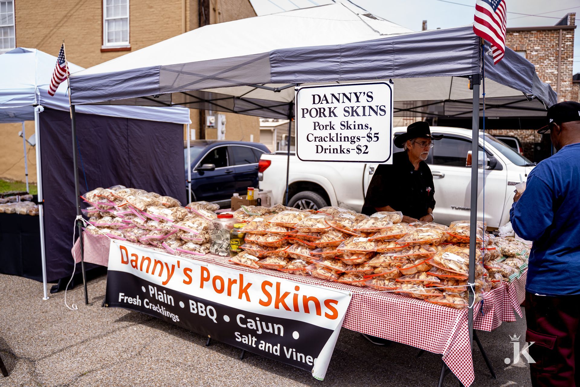 A man is standing behind a table selling pork skins.