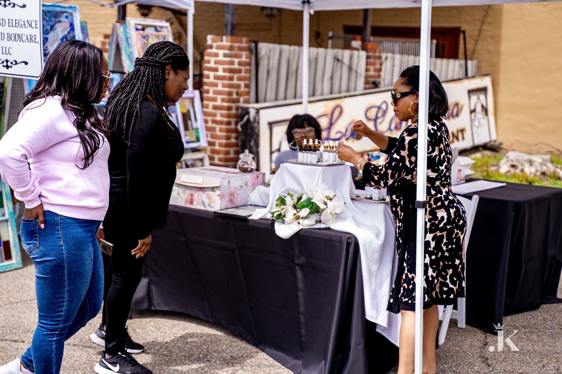 A group of women are standing around a table under a tent.