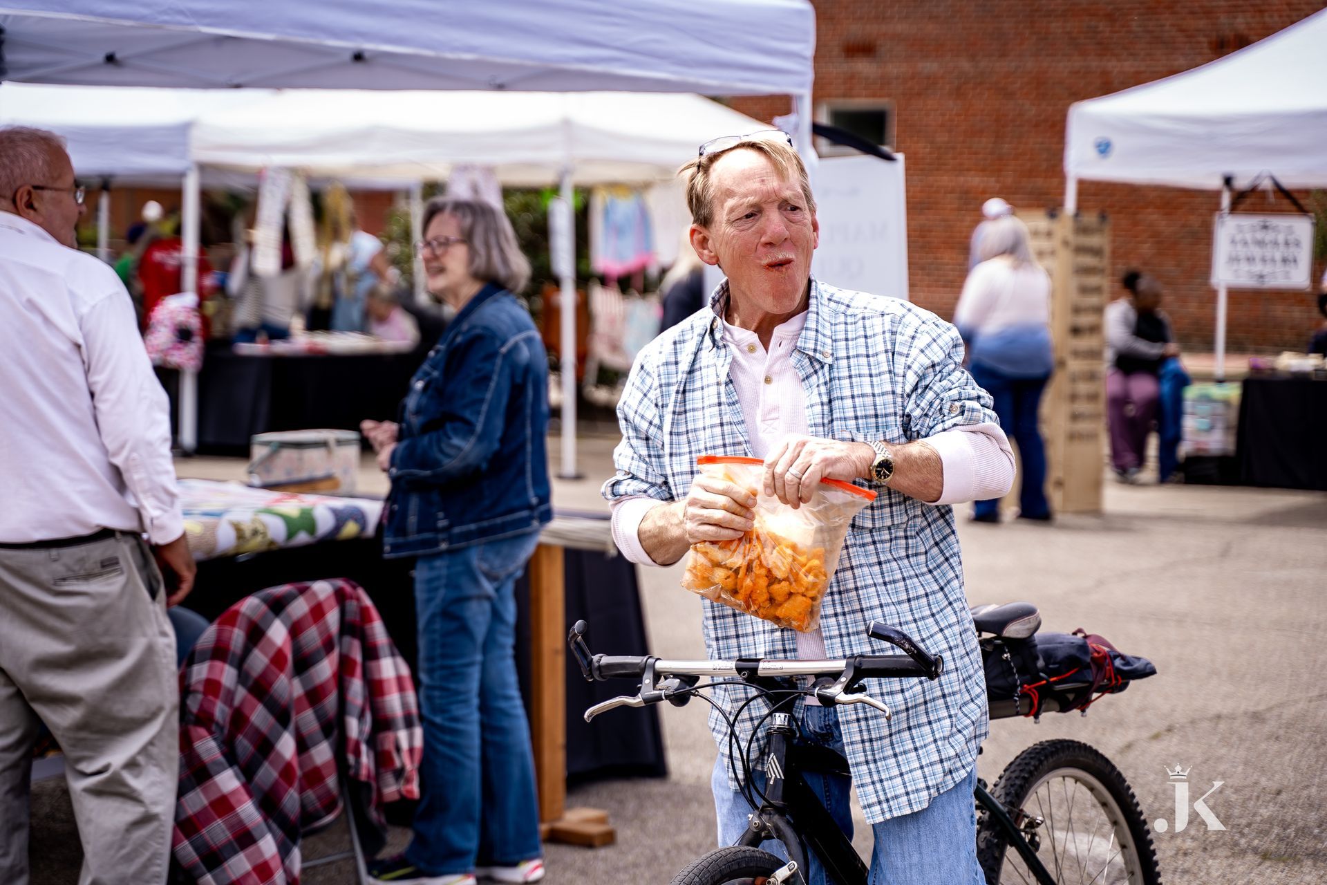 A woman is standing next to a bicycle holding a bag of chips.