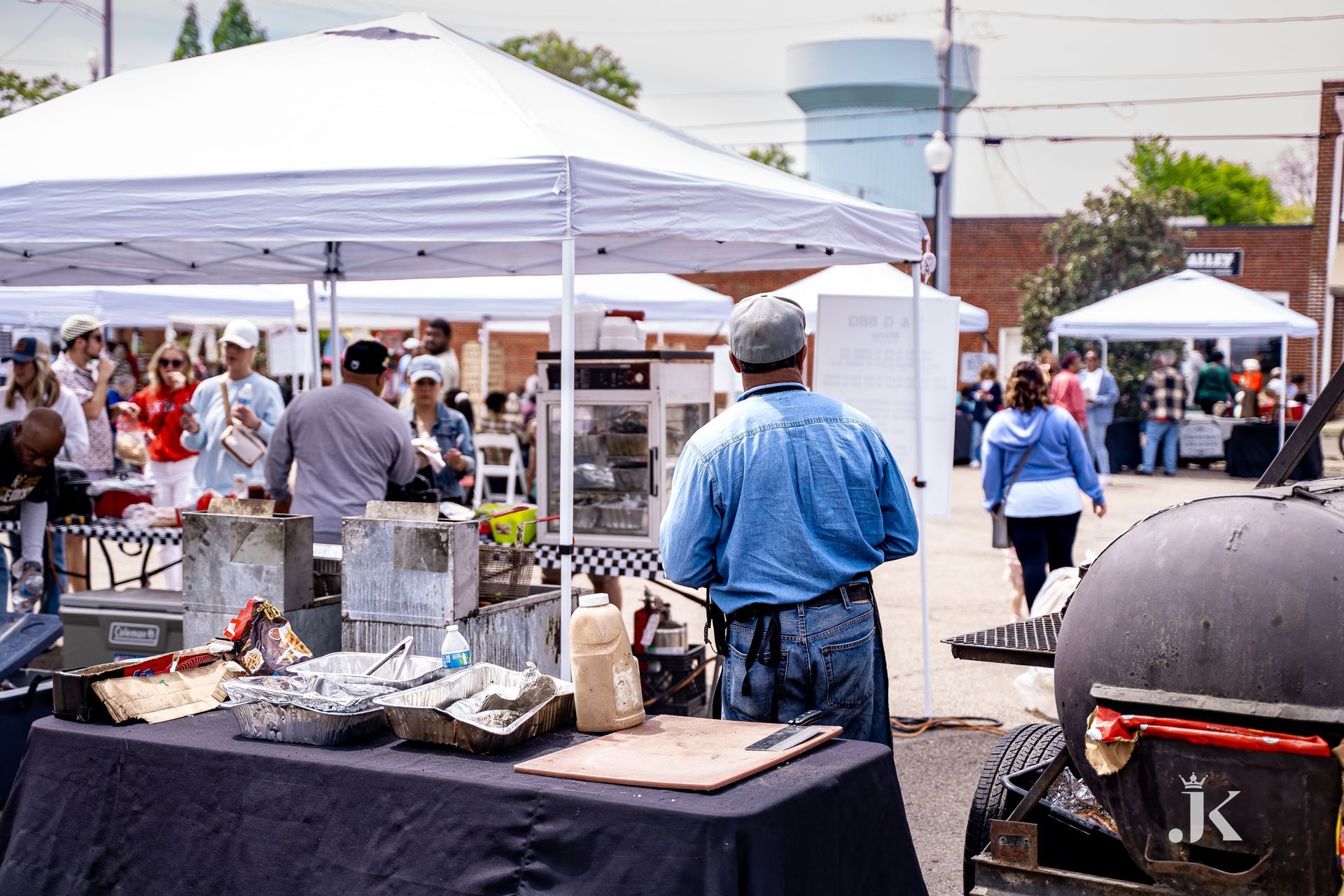 A man is standing in front of a table at a market.