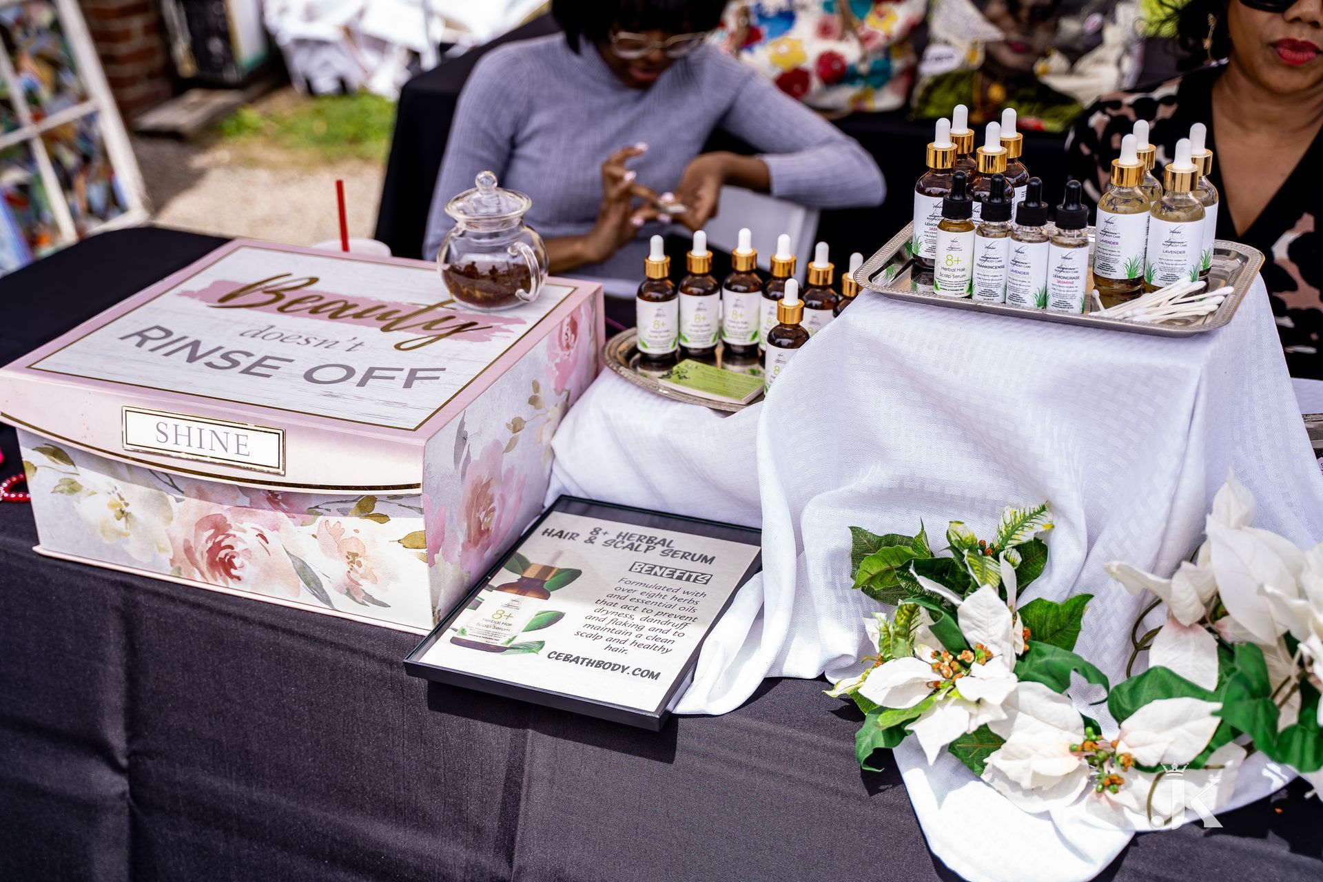A woman is sitting at a table with bottles of perfume on it.