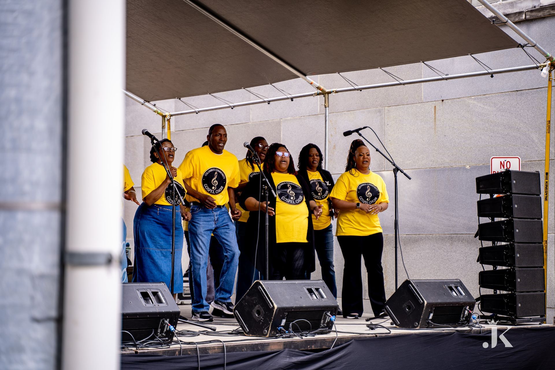 A group of people in yellow shirts are singing on a stage