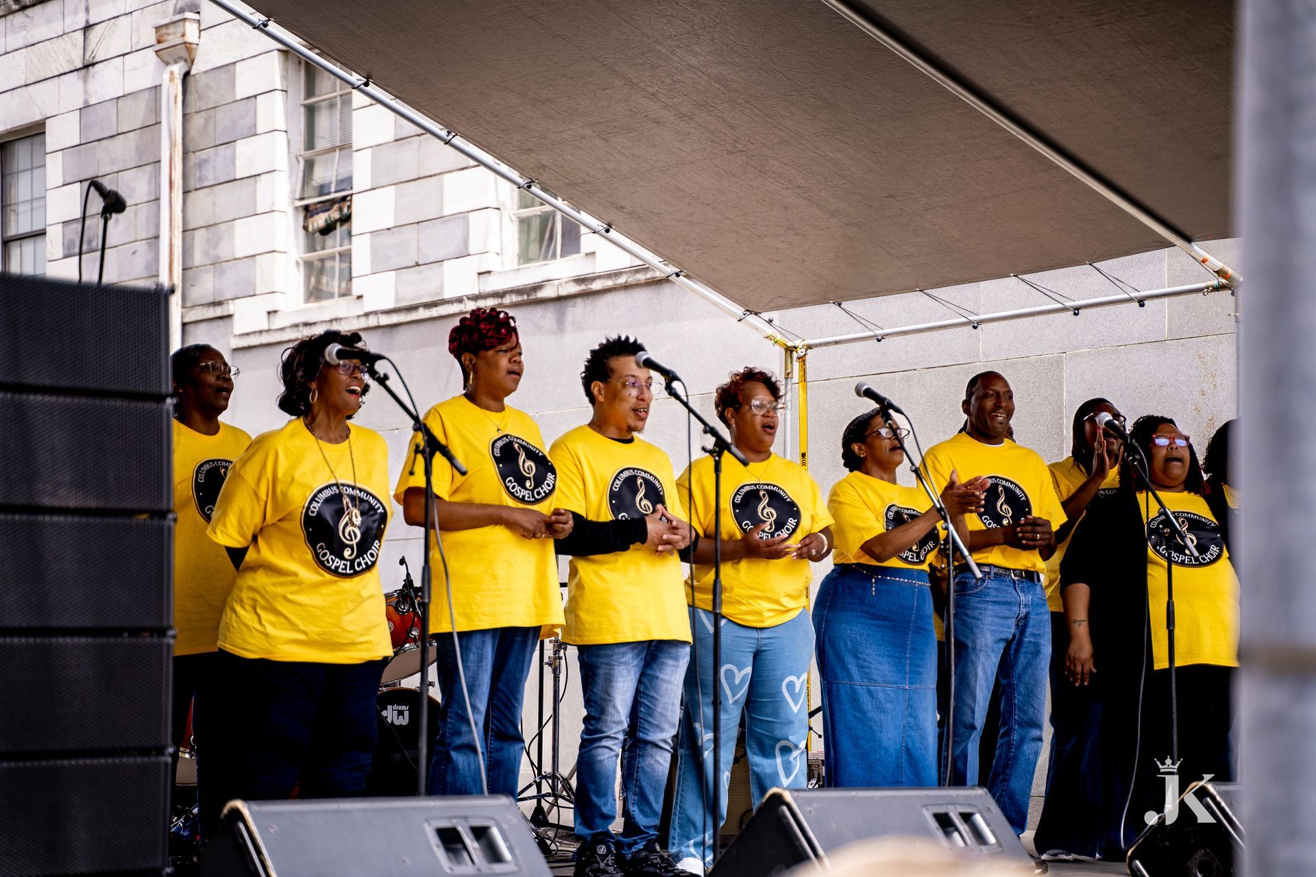 A group of people wearing yellow shirts singing into microphones