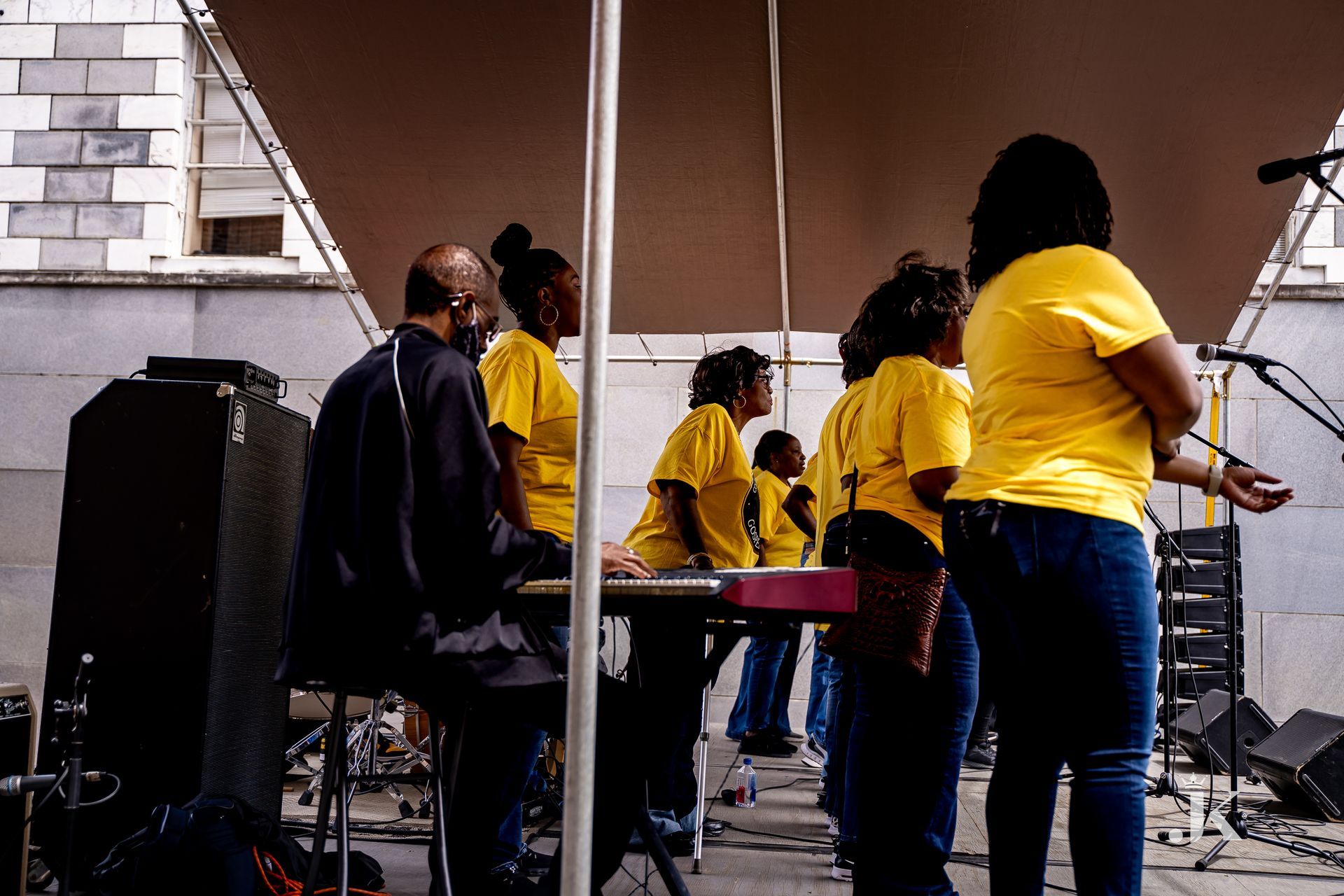 A group of people in yellow shirts are standing on a stage