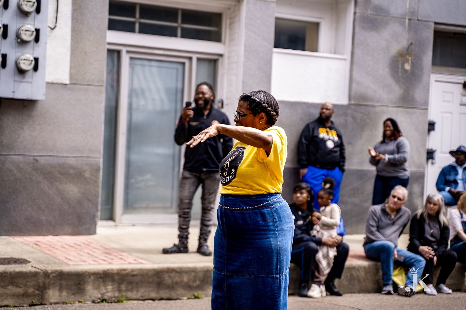 A woman in a yellow shirt is standing in front of a group of people.