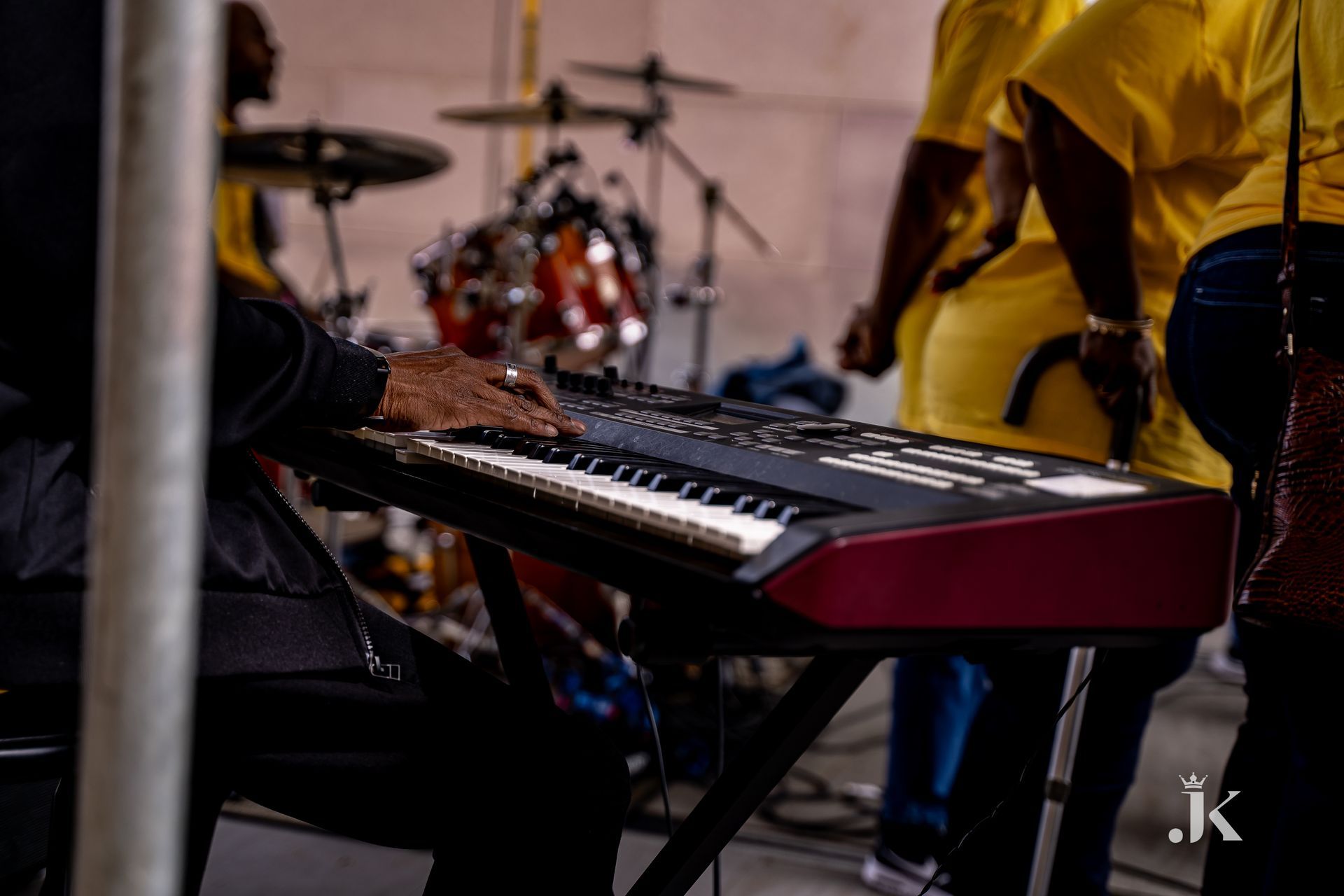 A man is playing a keyboard in front of a drum set.