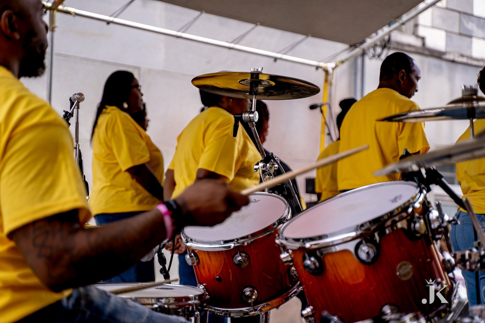 A group of people in yellow shirts are playing drums