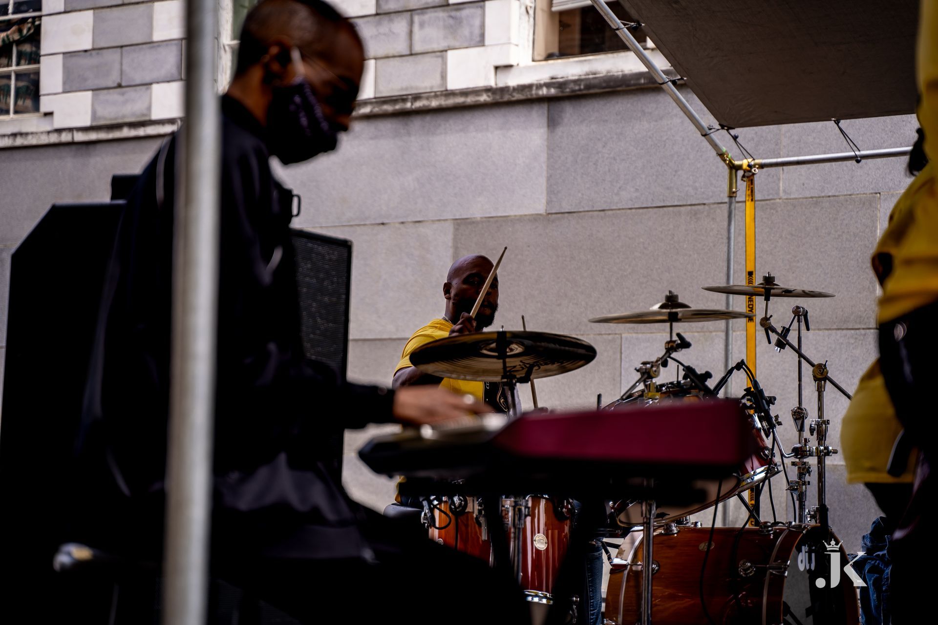 A man wearing a mask is playing drums on a stage.