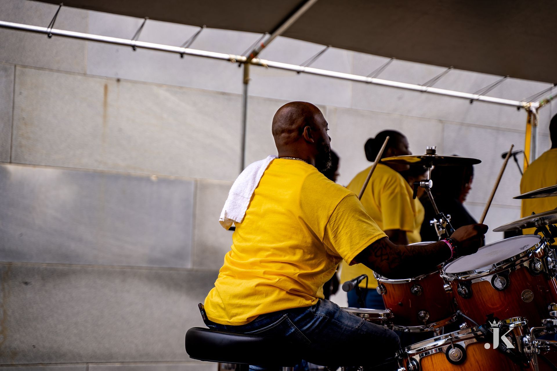 A man in a yellow shirt is playing drums