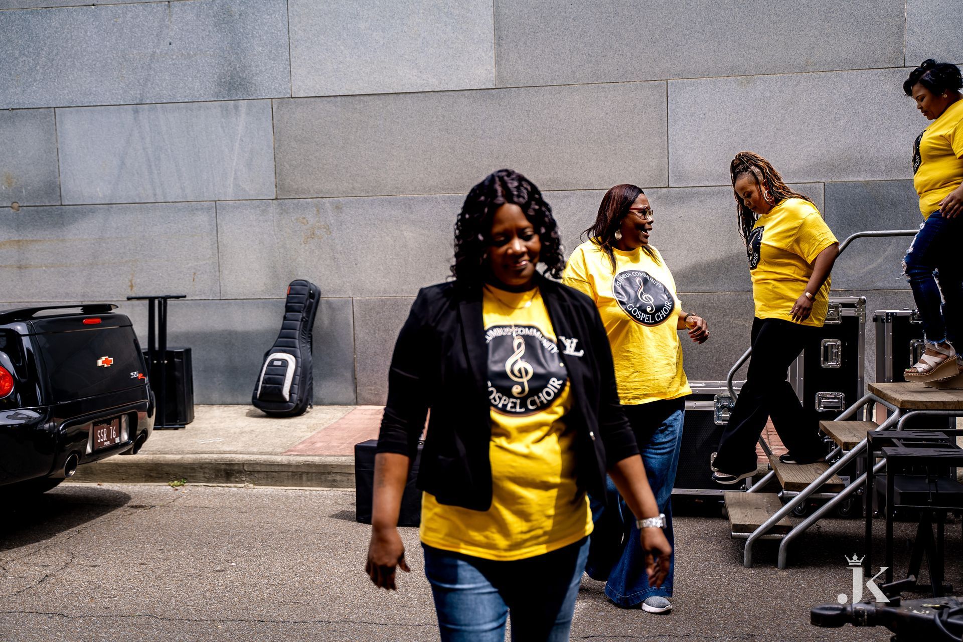A group of women wearing yellow shirts are walking down the street