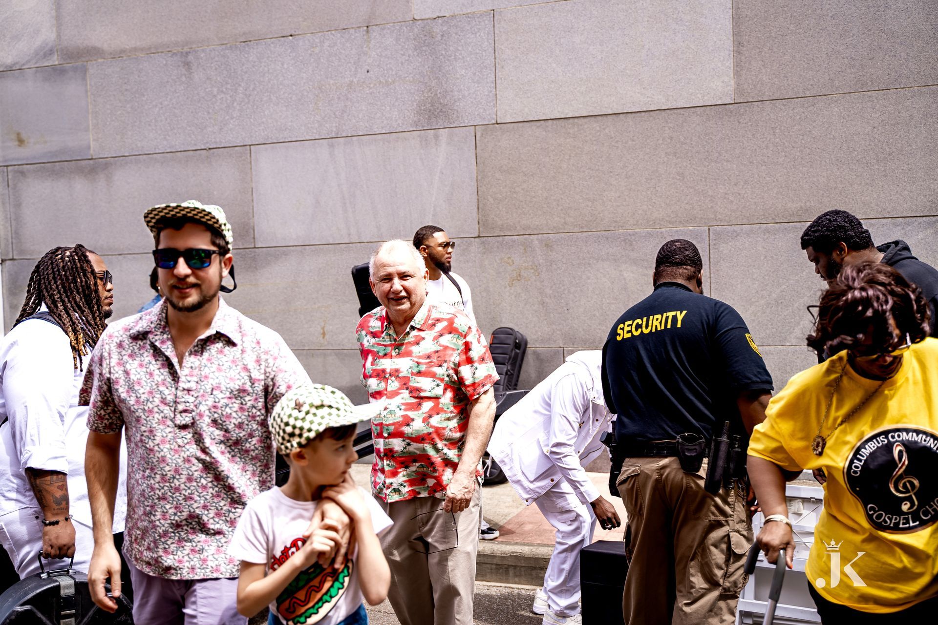 A man in a security shirt stands in a crowd of people