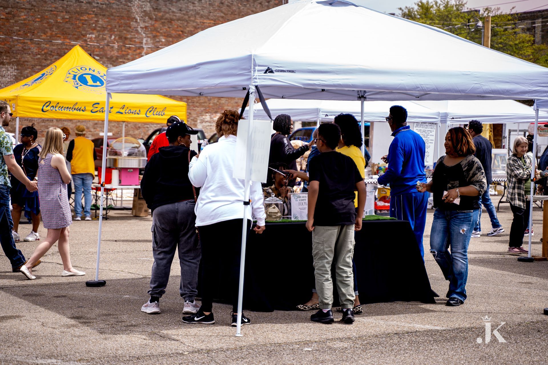 A group of people are standing around a table under a tent.