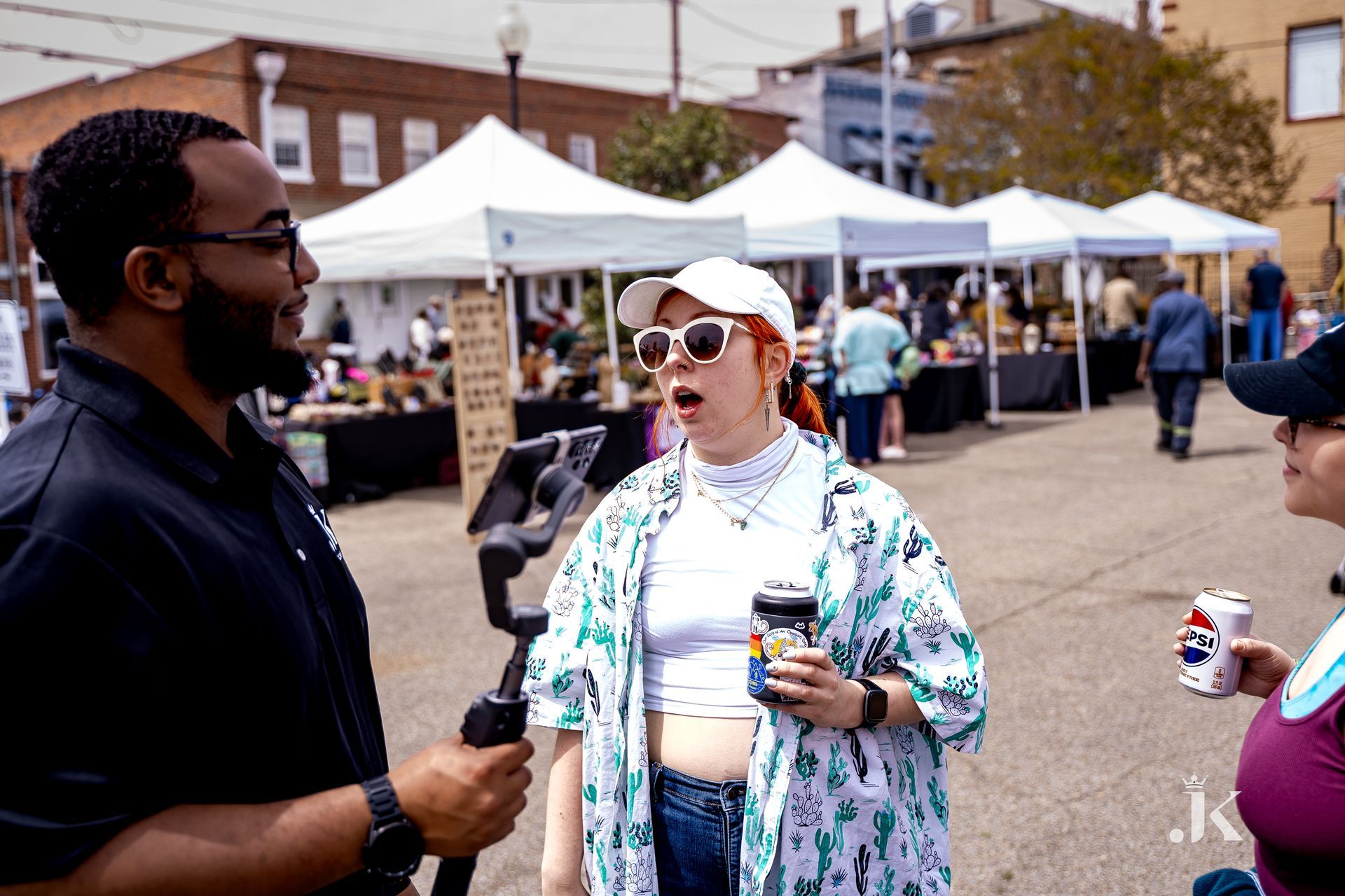 A man and two women are standing on a street talking to each other.