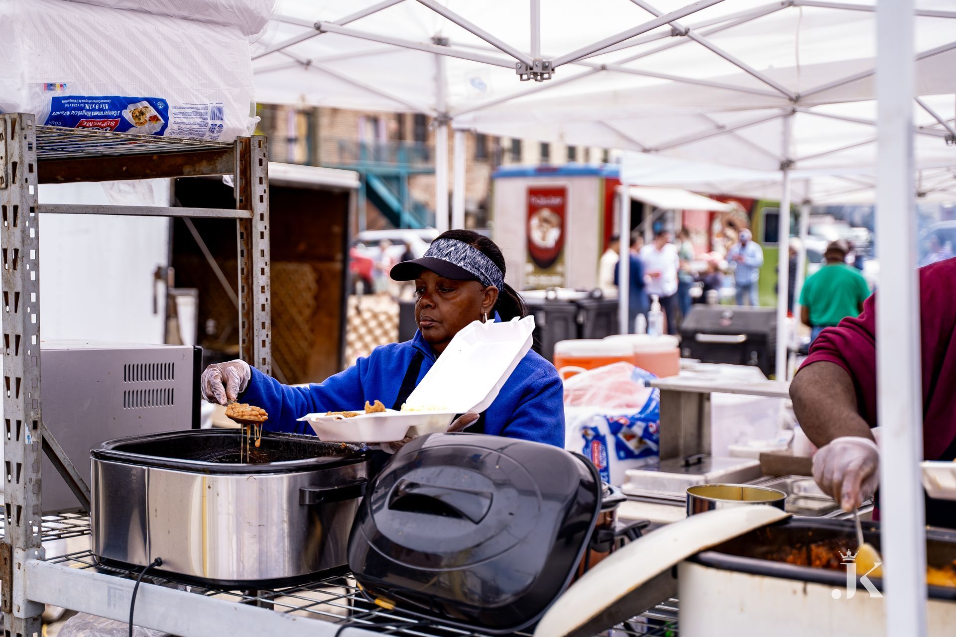 A woman is cooking food in a tent at a market.