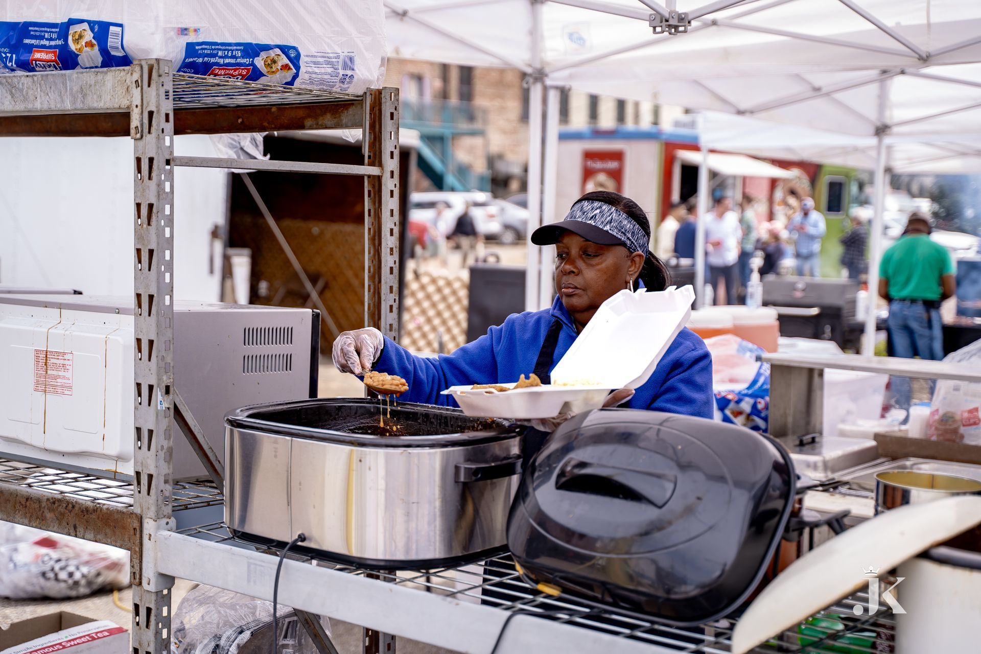 A woman is cooking food in a crock pot at a market.