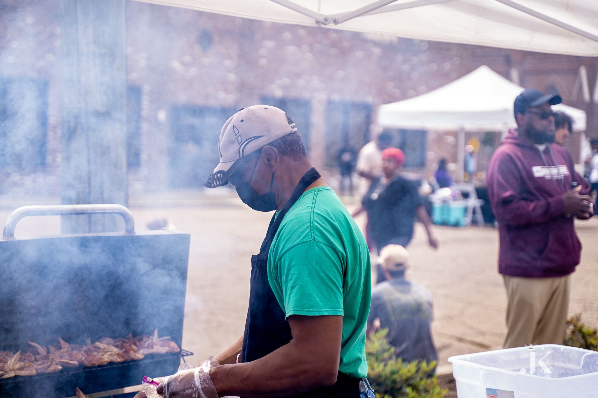 A man wearing a mask is cooking food on a grill.
