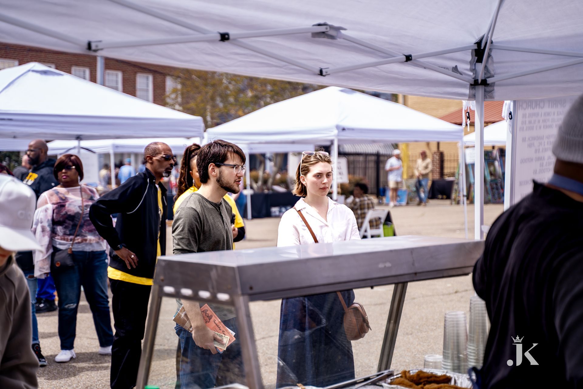 A group of people are standing around a food stand at a market.