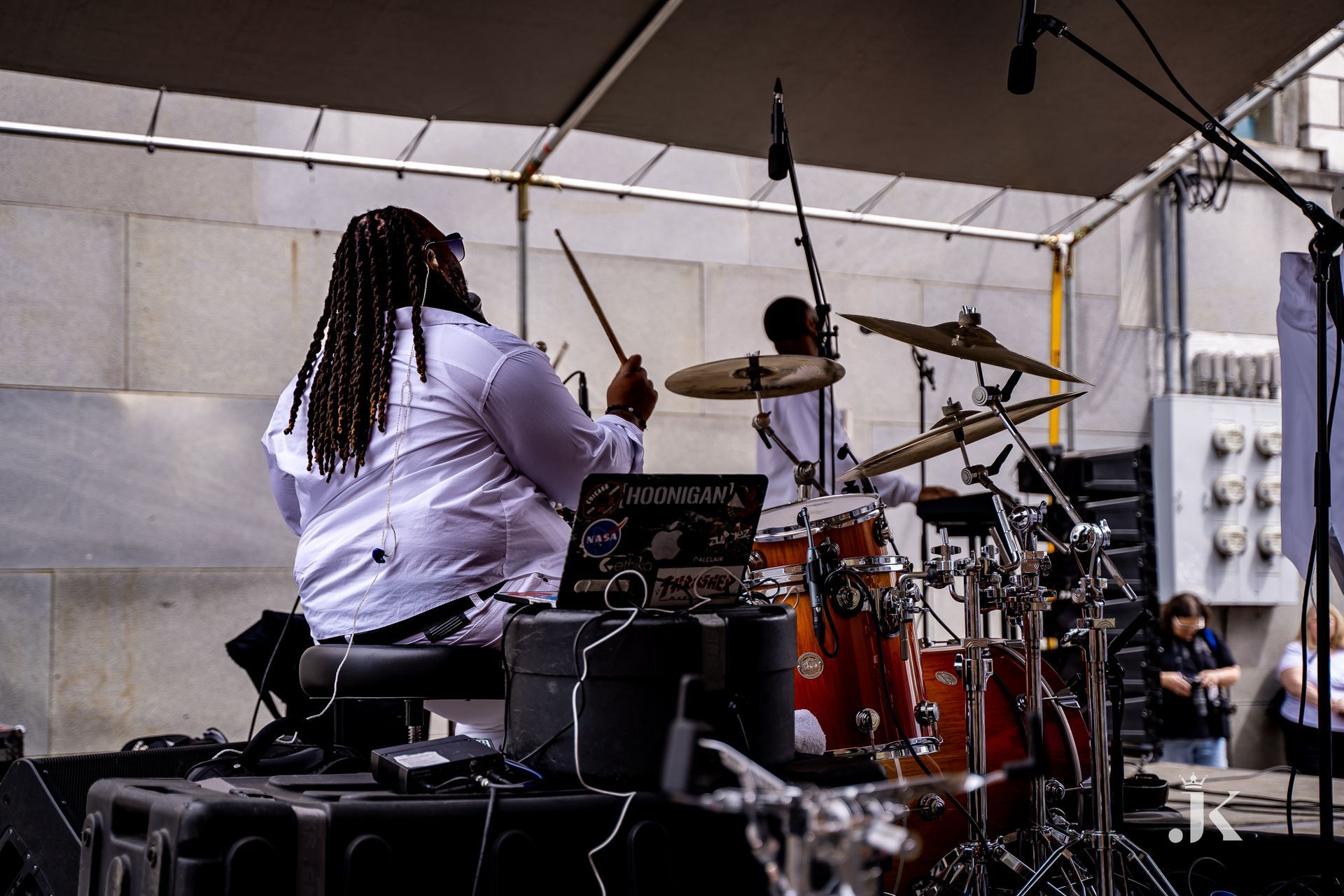 A man in a white shirt is playing drums on a stage