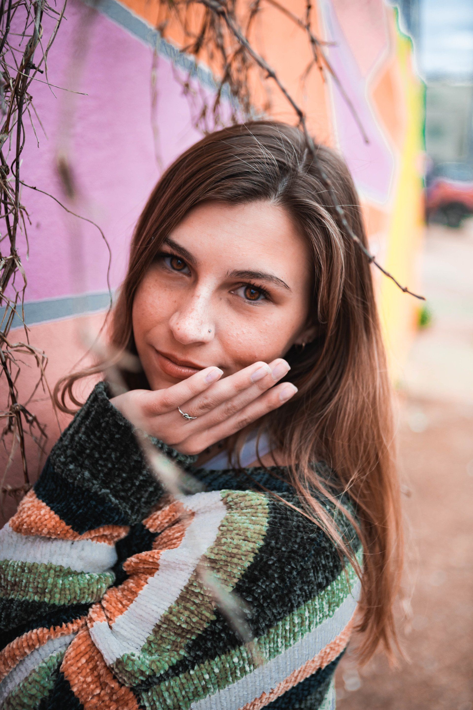 A woman in a striped sweater is covering her mouth with her hand.