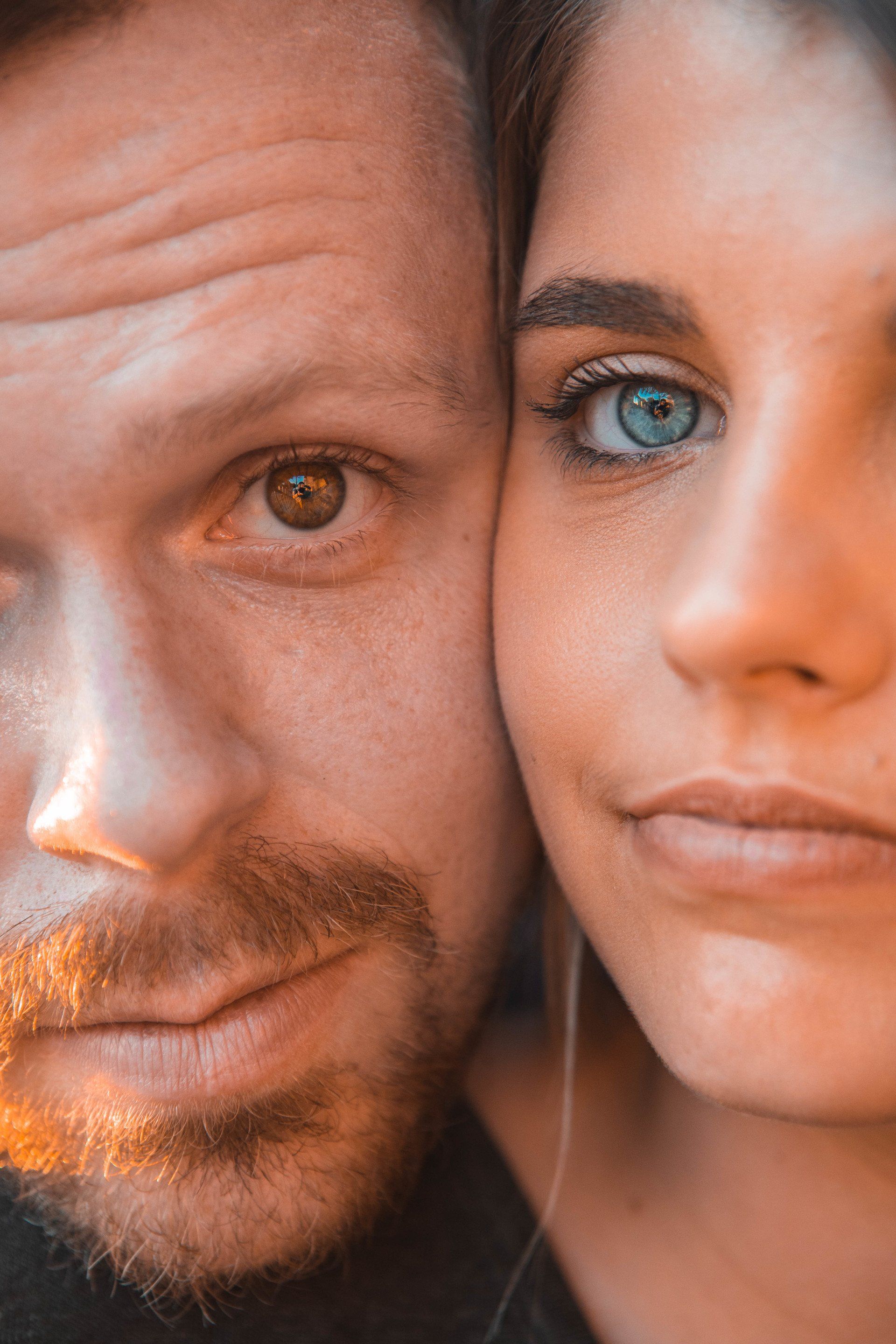 A close up of a man and a woman 's faces . the woman has blue eyes and the man has brown eyes.