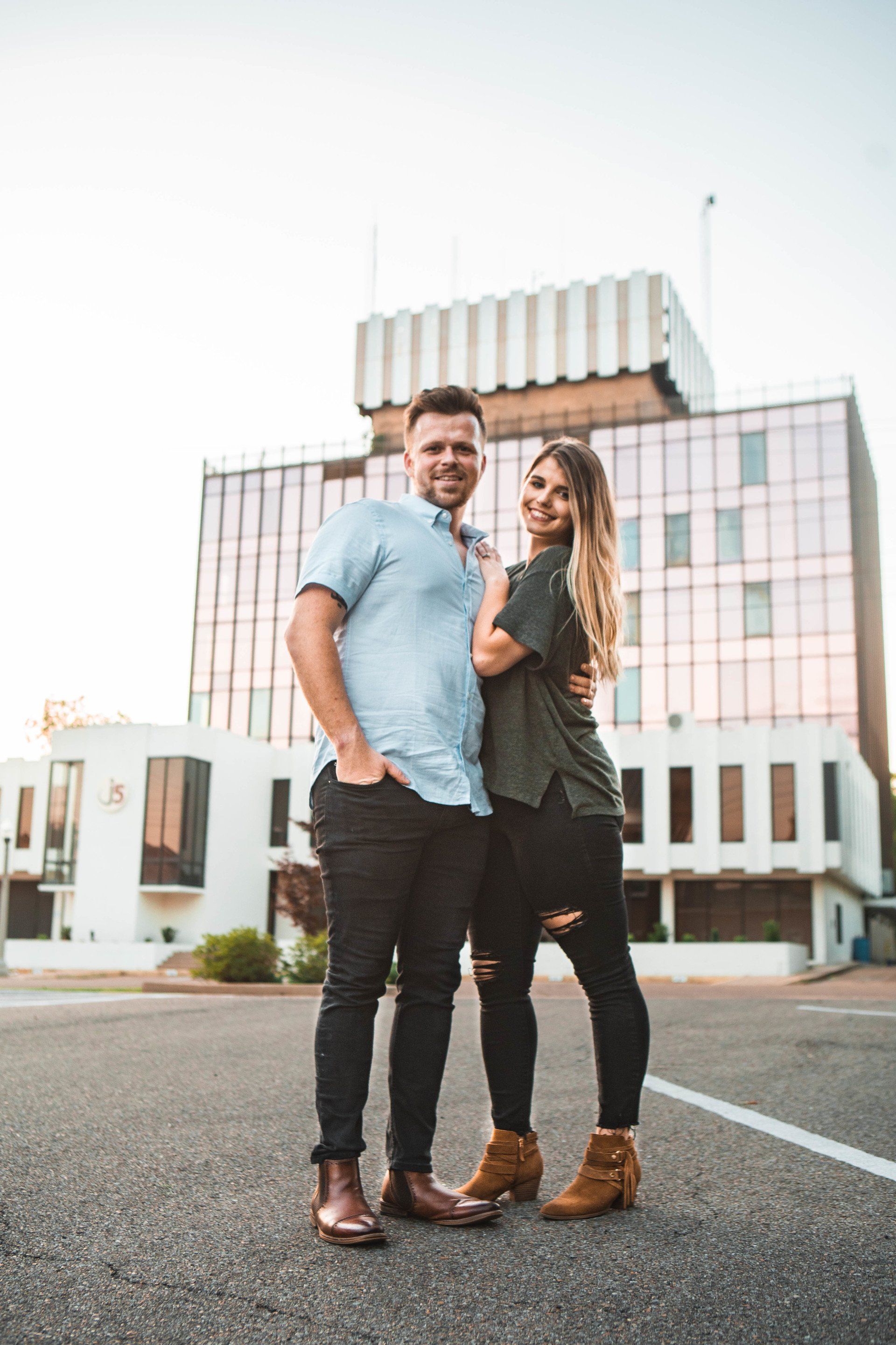 A man and a woman are standing next to each other in front of a building.