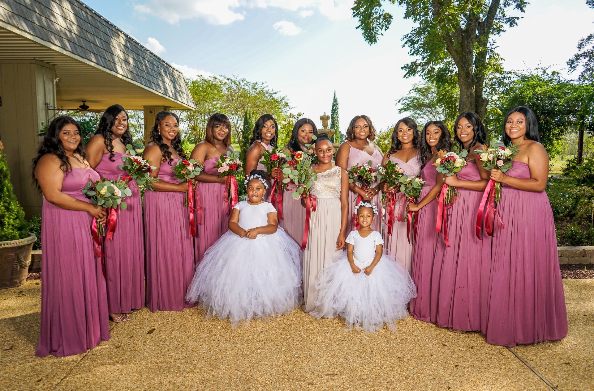 A bride and her bridesmaids and flower girls are posing for a picture.