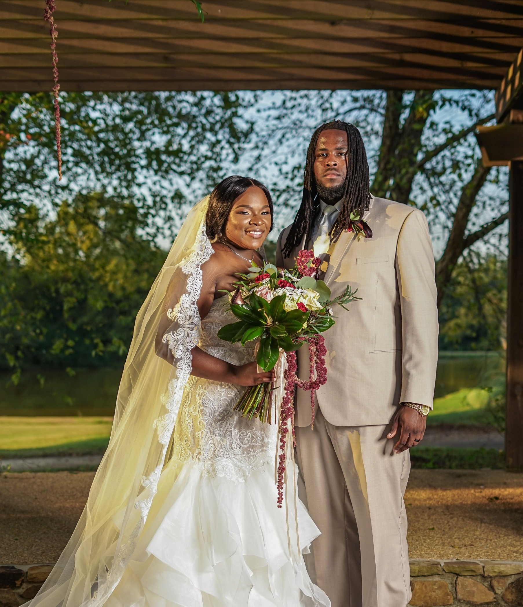 A bride and groom are posing for a picture under a canopy.