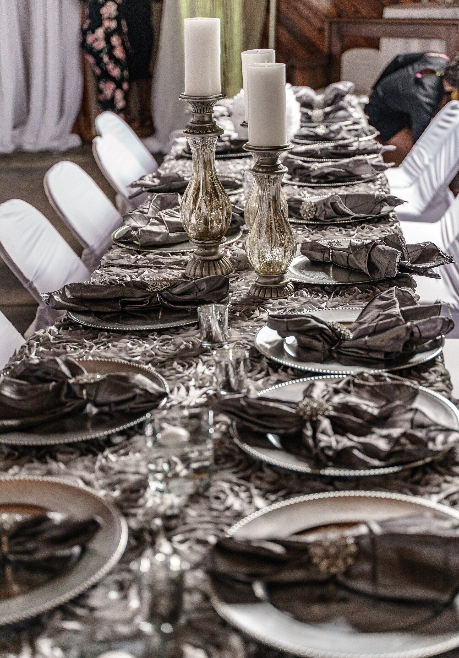 A long table with plates , napkins , and candles on it.