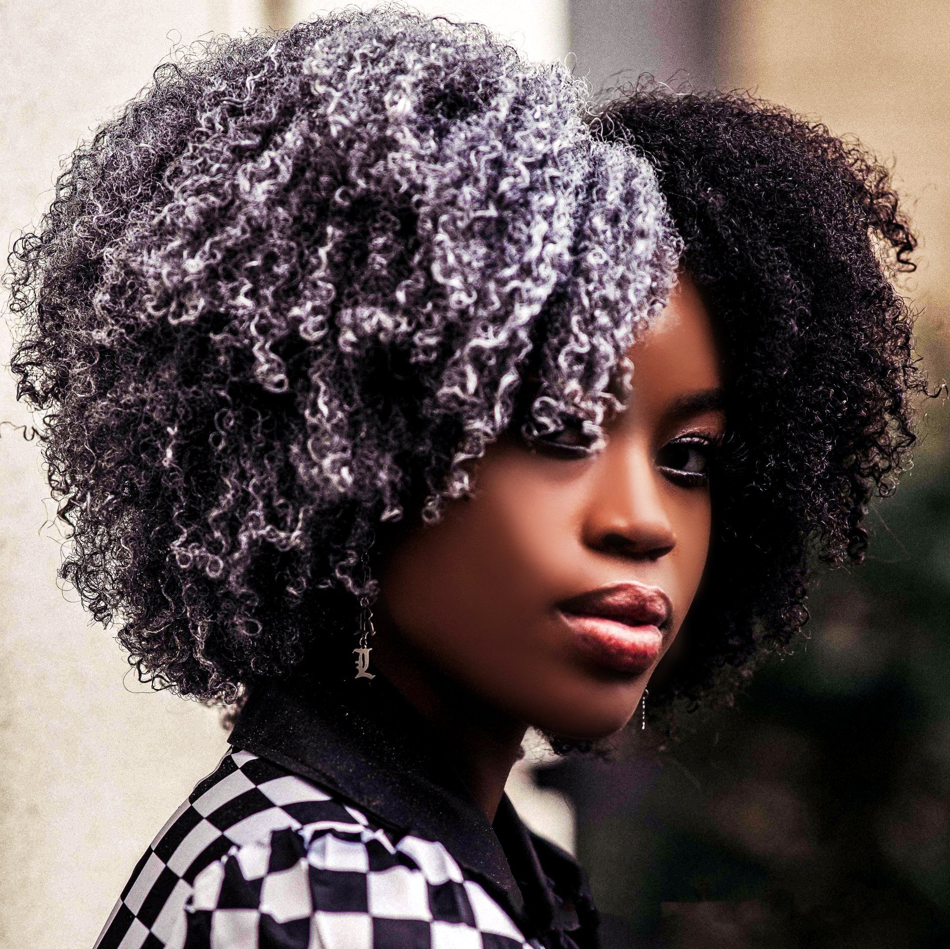 A woman with curly hair is wearing a black and white checkered jacket